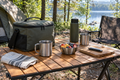 Camp kitchen table with cooler bag and mugs at a morning campsite