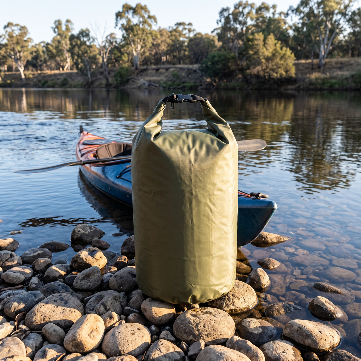 Dry bag on river rocks by a kayak